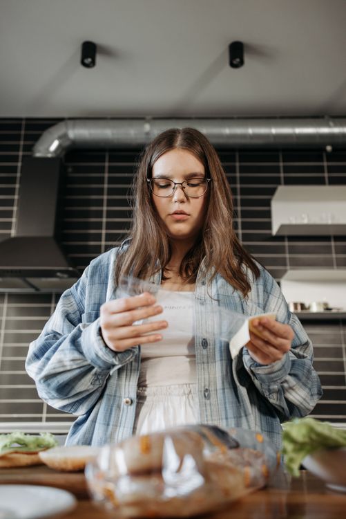 Woman reading food label on packaged product in kitchen